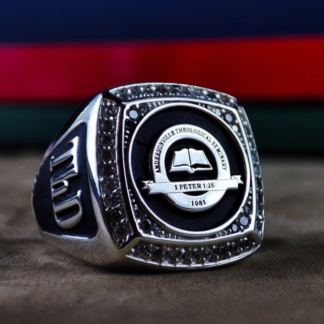 Custom men’s university ring with a central stone and engraved college emblem. Available in gold or silver, this ring is a unique way to celebrate academic milestones.