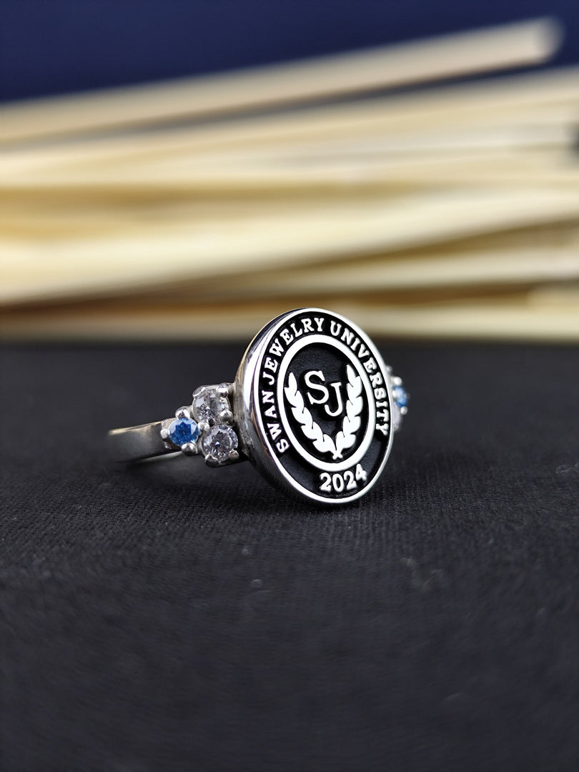 Silver women’s college ring with a central stone, engraved with a university crest. A perfect way to honor academic milestones, suitable for daily wear or special occasions.