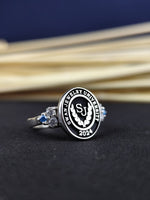 Load image into Gallery viewer, Custom graduation ring for women, featuring a university emblem and central stone. Available in gold or silver, this ring is a beautiful tribute to academic success.