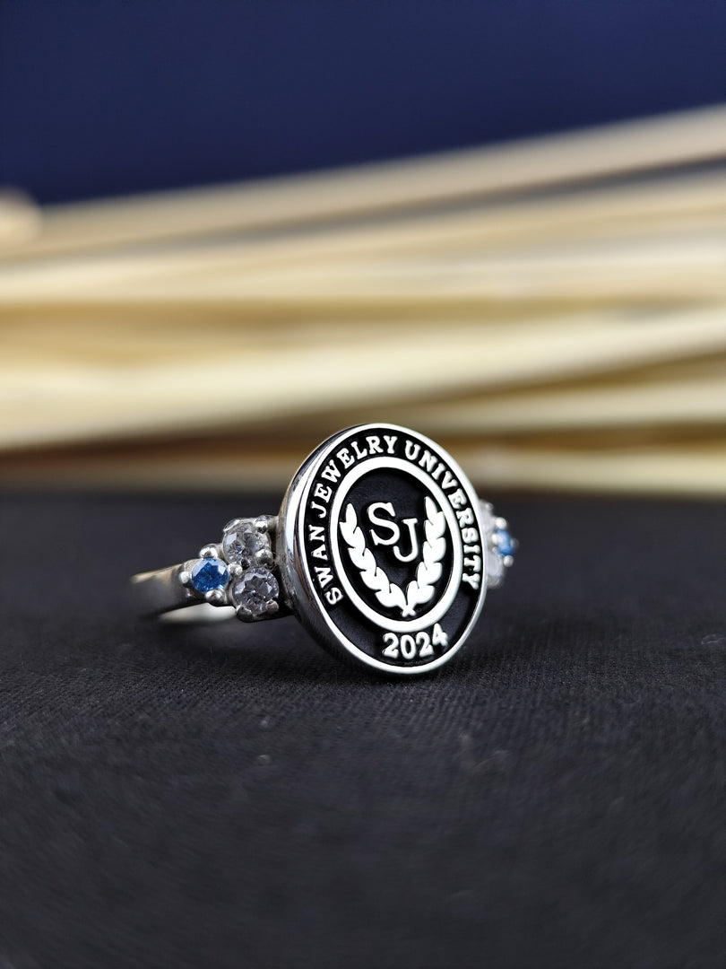 Custom graduation ring for women, featuring a university emblem and central stone. Available in gold or silver, this ring is a beautiful tribute to academic success.