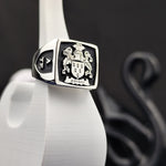 Load image into Gallery viewer, This custom silver heraldic signet ring features a recessed engraving of a coat of arms, enhanced with black enamel for a bold and elegant look. A unique family crest ring for those who cherish history and legacy, this square design offers a regal and distinguished presence. Perfect as a keepsake, heirloom, or meaningful personalized gift.