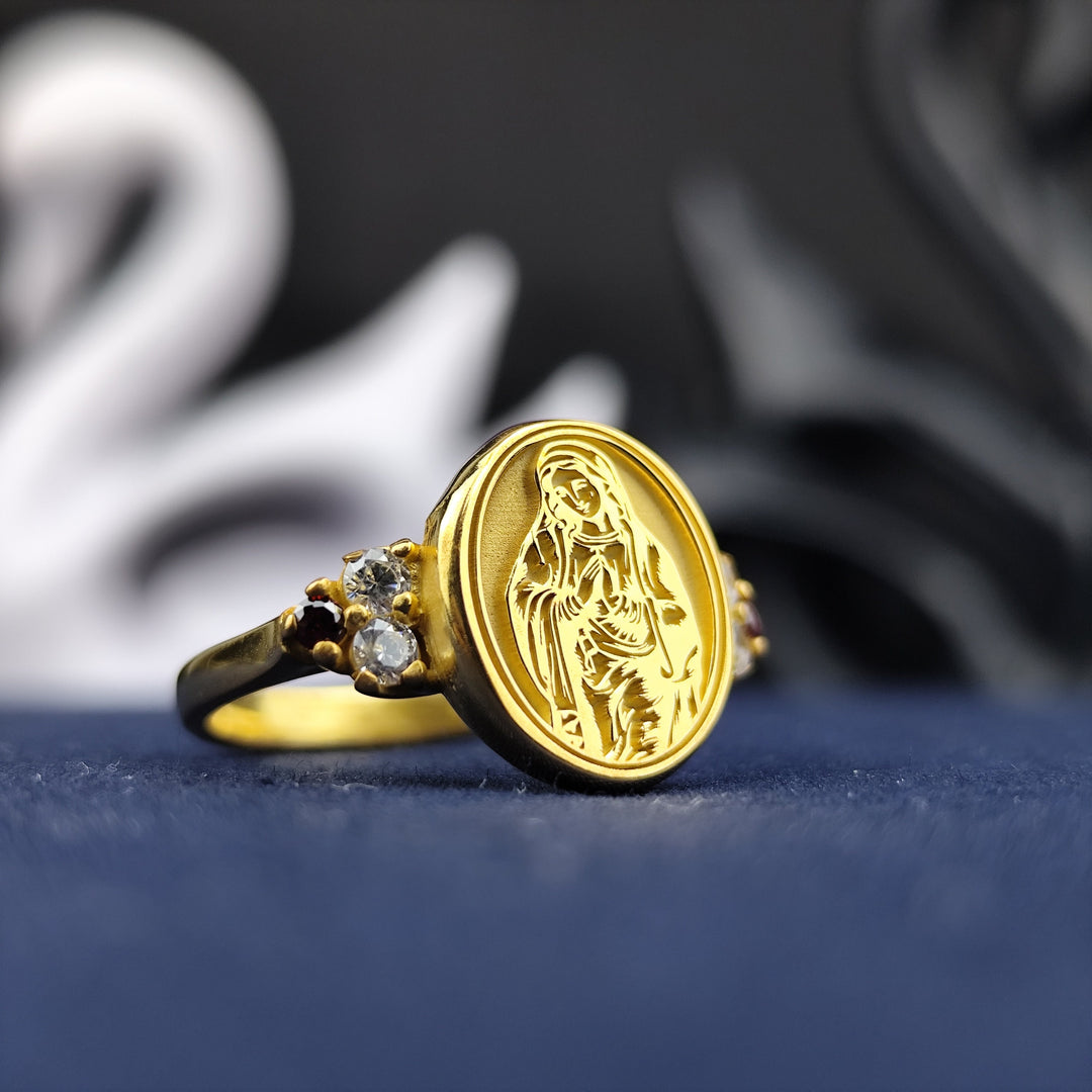 A refined and sophisticated religious ring featuring the Blessed Virgin Mary, crafted in gold-plated material with a sparkling gemstone. This women's signet ring is a delicate yet powerful representation of faith, devotion, and elegance. A timeless Catholic jewelry piece that makes a beautiful and personal gift for believers and those with a deep spiritual connection.