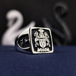 Load image into Gallery viewer, Celebrate your heritage with this custom square heraldic ring, featuring a black enamel-coated engraved family crest. A unique and meaningful heirloom piece, this silver signet ring is designed for those who take pride in their lineage. Whether as a gift or a personal keepsake, this noble jewelry piece represents strength, tradition, and legacy.