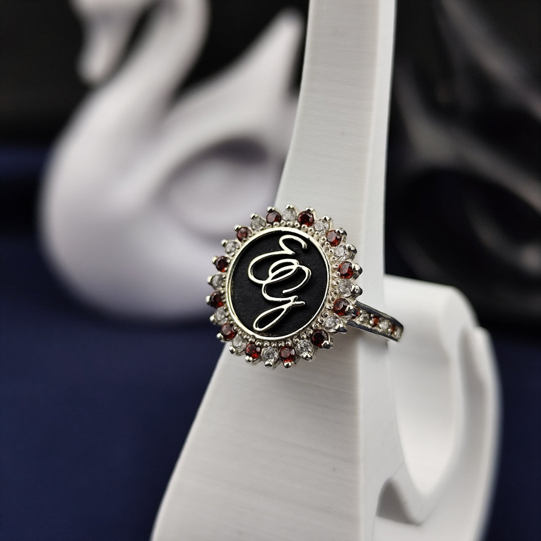 A stylish and modern silver monogram ring for women, featuring two engraved initials with an elegant enamel coating. The gemstone accent adds a luxurious feel to this customizable signet ring. Whether as a family heirloom, surname ring, or personal keepsake, this jewelry piece is designed for timeless elegance.