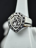 Load image into Gallery viewer, Celebrate your ancestry with this exquisite shield signet ring, engraved with a detailed family crest and adorned with black and white stones. A timeless and meaningful jewelry piece, this coat of arms ring represents noble lineage and personal pride. A striking heirloom for collectors or individuals who appreciate heritage-inspired jewelry.