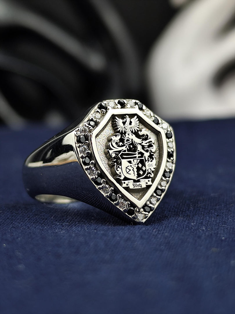 This shield family crest ring is a stunning heraldic piece, featuring a deep engraving of a coat of arms with contrasting black and white stones. Crafted for those who appreciate history and noble heritage, this custom signet ring is a striking heirloom. A powerful and elegant jewelry item, perfect for gifting or personal wear.