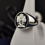 Load image into Gallery viewer, A bold and elegant round heraldic ring, designed in sterling silver with a custom coat of arms engraving and black enamel detailing. This unique family crest ring is a sophisticated heirloom that symbolizes history and tradition. A perfect gift for those who wish to honor their family name with a timeless and personalized piece of jewelry.