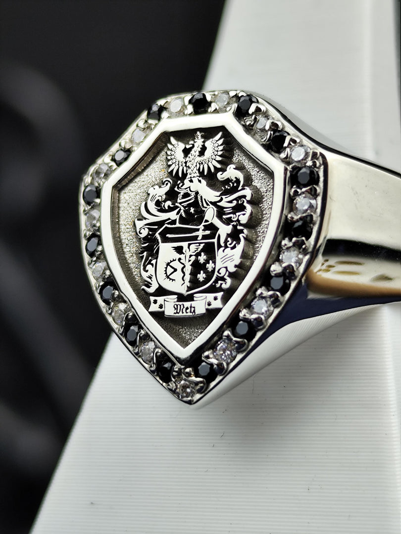 This custom shield-shaped family crest ring is an elegant blend of history and craftsmanship. Featuring an engraved coat of arms with black and white stones, this ring is designed to showcase personal heritage. A regal and refined accessory, perfect as a distinguished heirloom or a meaningful symbol of lineage, crafted for those who value tradition.